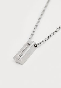 Colier argintiu cu un pandantiv rectangular cu un centru deschis, atașat de un lanț elegant și flexibil cu un design geometric.