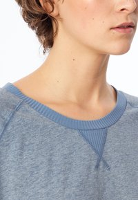 Sudadera azul jaspeada con cuello canalé y costuras en los hombros, con una textura suave y un corte relajado.