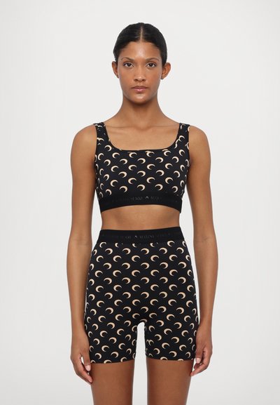 Černý dvoudílný sportovní set obsahující crop top s čtvercovým výstřihem a šortky s vysokým pasem, zdobený vzory půlměsíce v béžové barvě.