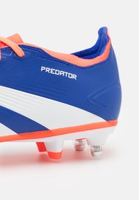 Scarpino da calcio blu con accenti bianchi e dettagli arancioni, caratterizzato da una superficie testurizzata, colletto imbottito e tacchetti traslucidi.