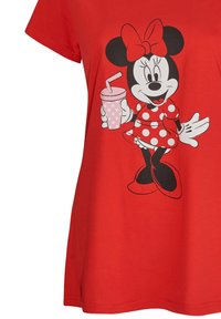 Camiseta roja con un gráfico de un personaje de dibujos animados sosteniendo una bebida rosa con una pajita. El personaje lleva un vestido de lunares y un lazo.