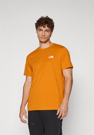 Orange bomulds T-shirt med korte ærmer, med et hvidt logo på venstre bryst. Rund hals og en glat tekstur.