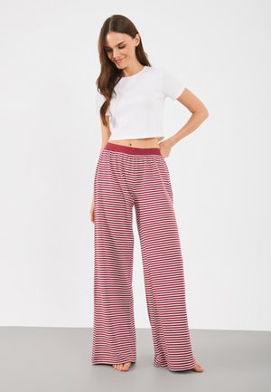 White cropped t-shirt paired with wide-legged, red and white striped pants with an elastic waistband. Smooth fabric texture, casual fit.