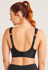 Svart sport-bh med justerbara band och en hake-och-öga-stängning, med en slät yta och en bred rem för stöd.