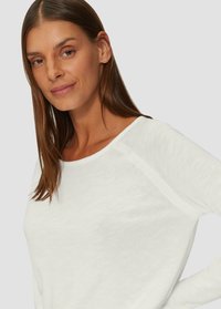 Haut blanc léger à manches longues avec un large décolleté et des manches raglan. Texture douce, design minimal et coupe décontractée.