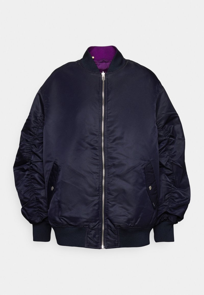 Veste bomber bleu marine avec fermeture éclair à l'avant, poignets et ourlet côtelés, poches latérales à rabat avec boutons, et doublure violette visible au niveau du col.