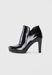 Bottine en cuir verni noir à bout arrondi, talon haut et sans lacets. Présente une texture lisse et brillante ainsi qu'un design épuré.