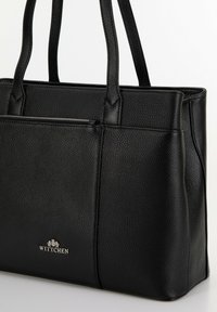 Zwarte leren handtas met een textuurafwerking, voorzien van twee handvatten en een ritsvak, gemarkeerd met een zilveren "WITTCHEN" logo.