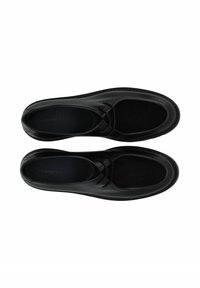 Chaussures en cuir noir à finition lisse, avec un panneau en daim et un design minimaliste, bout arrondi et accents élastiques.