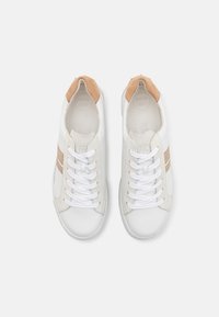 Sneaker bianche con una finitura testurizzata, caratterizzate da un tallone in suede marrone chiaro, lacci bianchi e strisce metalliche dorate sui lati.