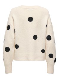 Pull couleur crème avec de grands pois noirs dispersés sur les manches et le dos, avec poignets et ourlet côtelés.