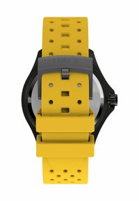 Montre noire avec un bracelet en silicone jaune présentant un design perforé. Comprend un boîtier argenté et une boucle en métal pour la fermeture.