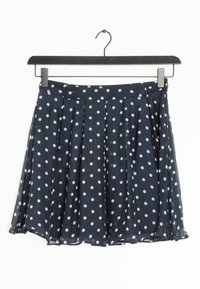 Marinblå prickig kjol i lätt material, med veck, midjeband och design som slutar ovanför knäet. Mjuk textur.