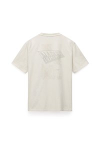 Kort cremefarvet t-shirt lavet af blødt bomuld. Har et stort, subtilt grafisk print med teksten "NAPAPIJRI" og "1987" på ryggen.