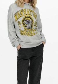 Felpa grigia con cappuccio, caratterizzata da una stampa grafica gialla e nera con la scritta "MANHATTAN BROOKLYN 1986" e un simbolo di cobra, vestibilità comoda.
