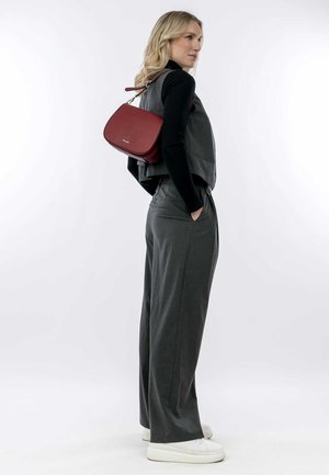 Gray tailored vest and wide-leg pants, paired with a red leather crossbody bag. Model wears white sneakers, hair down. Plain background.