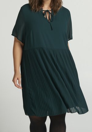 Dunkelgrünes Kleid mit einem plissierten unteren Abschnitt, kurzen Ärmeln und einem Schlüsselloch-Ausschnitt, der mit einem Band gebunden ist. Fließender Stoff mit glatter Textur.