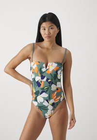 Bloemige eenpiece badpak met een groene achtergrond en witte, oranje en paarse bloemen; heeft dunne verstelbare bandjes en een V-hals ontwerp.