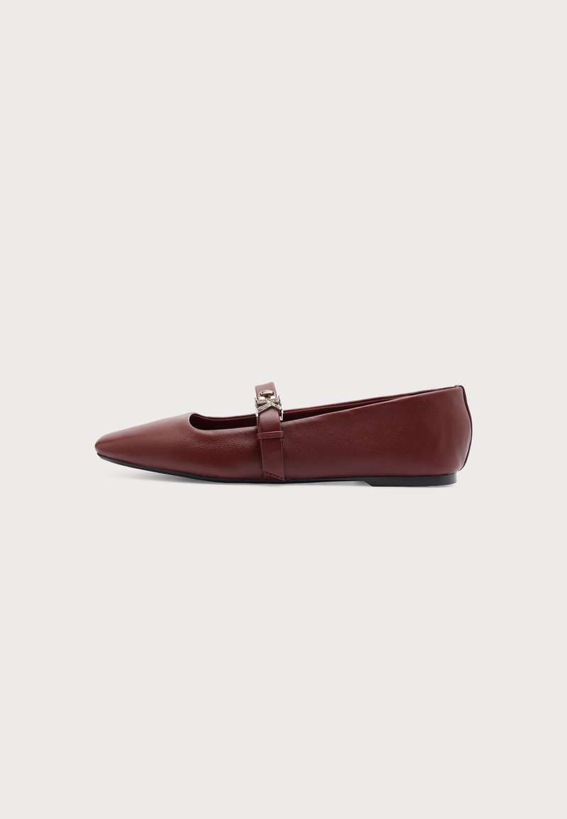 Chaussure plate Mary Jane en cuir rouge foncé à bout pointu avec un détail boucle argentée sur la bride sur fond uni.