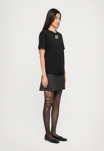Μαύρο βαμβακερό t-shirt με κοντά μανίκια και λογότυπο στο στήθος, συνδυασμένο με γκρίζα τζιν φούστα κα�ι μαύρες σκισμένες καλσόν.