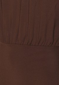 Brun klänning i tyg med rynkad textur upptill och en slät nederdel. Mjukt, stretchigt material med en enfärgad design.