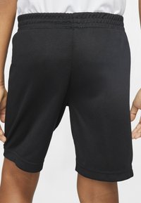 Black athletic shorts made from textured fabric. Features elastic waistband and visible stitching at the hem. Simple and functional design.