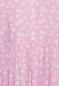 Tecido rosa com um padrão floral, adornado por flores brancas e pequenos centros roxos. O material parece suave, com uma textura franzida na barra.