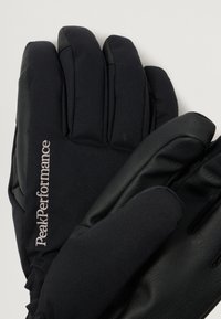 Black gloves featuring a combination of soft fabric and leather, with a logo embroidered in silver on the wrist area.
