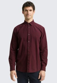 Chemise à manches longues à carreaux rouge foncé et noire. Devant boutonné avec un col standard. Tissu doux avec une texture lisse.