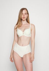 Světle béžová podprsenka s hladkým tvarovaným designem a nastavitelnými ramínky, spárovaná s krajkovými kalhotkami s vysokým pasem a květinovými vzory.