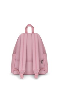 Mochila rosa con tirantes ajustables acolchados, dos bolsillos laterales, un bolsillo frontal con cremallera y un asa de transporte en la parte superior. Textura de tela suave.