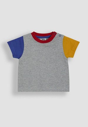 Pelēks īsām piedurknēm T-krekls ar sarkanu apkakli, zilu kreiso piedurkni un dzeltenu labo piedurkni. Īpaši izstrādāts ar plecu pogu, lai vieglāk uzvilktu.