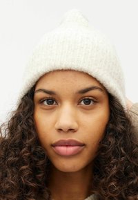 Berretto bianco a maglia con texture a coste e punta. Tessuto morbido e caldo, adatto per il freddo.