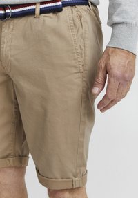 Khaki shorts med oppbrett, laget av bomull, med sidelommer og et strukturert liv med marineblå, rød og hvit stripe.