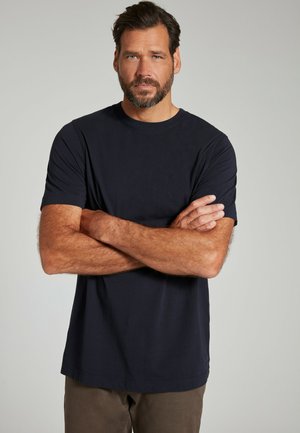 Marineblå t-shirt med rund hals i blødt materiale, korte ærmer, afslappet pasform. Båret af en person med armene over kors.