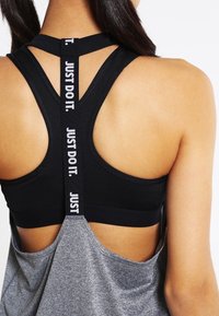 Svart atletisk linne med racerback-design, med grå botten och framträdande "JUST DO IT."-text på remmarna. Slät textur.