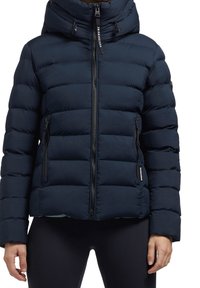 Donkerblauwe donsjas met capuchon, voorzien van horizontale doorgestikte panelen, een ritssluiting aan de voorkant en ritszakken aan de zijkant. Glad oppervlak.