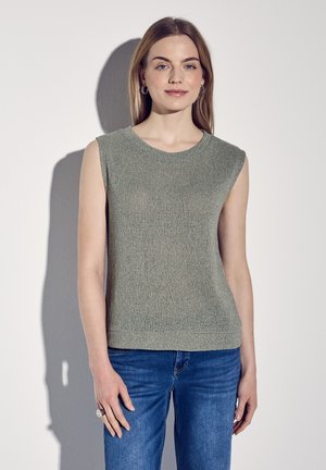 Sleeveless, light green knitted top with a round neck. Soft texture, semi-fitted design, and subtle sheen, paired with blue jeans.