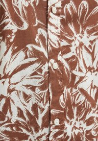 Pruun ja valge lillemuster, nupuga kinnitamine, tekstureeritud disain kerges tekstiilis.