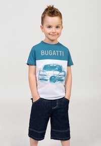 T-shirt azzurro chiaro e bianco con illustrazione e logo di una Bugatti, abbinato a pantaloncini di jeans scuri con risvolti.