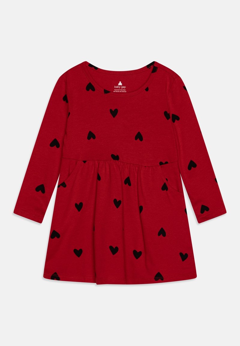 Robe longue à manches longues rouge pour bébé avec des motifs de cœurs noirs, taille froncée, et encolure ronde, étiquetée "baby gap" à l'intérieur du col.