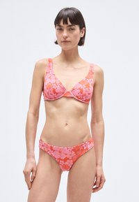 Blomstret bikini sæt med pink og orange mønster, lavet af blødt stof. Toppen har brede stropper og en rynket midte; bunden er lavtaljet.