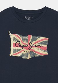 Tmavě modré bavlněné tričko s potiskem opotřebované vlajky Union Jack a nápisem "Pepe Jeans LONDON" červenou barvou přes střed.