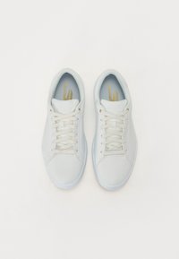 Light blue sneakers with a smooth texture, featuring white laces, gold accents, and a rounded toe design. Flat rubber soles included.