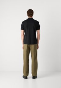 Black polo shirt and olive pants. The shirt features short sleeves and a collar. Pants are straight-leg with a smooth texture and two side pockets.