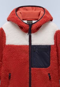 Red and cream fleece jacket with a hood, textured fabric, navy accents, and a zippered pocket on the left chest. Features adjustable drawstrings.