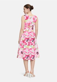 Blumendruckkleid mit rosa und weißen Farbtönen, ärmellosem Design und einem Cut-out-Detail auf dem Rücken. Weicher Stoff mit einer ausgestellten Silhouette.