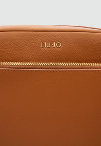 Braune Lederhandtasche mit strukturiertem Design. Verfügt über einen Reißverschluss in goldfarbener Ausführung und ein geprägtes "LIU·JO"-Logo. Glatte Oberfläche mit sichtbarer Maserung.