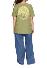 Olivengrünes T-Shirt mit kurzen Ärmeln, das ein großes gelbes Sonnenmuster und den Text "LASSE DIE SONNE IN DEINEM HERZEN" auf dem Rücken bedruckt hat.