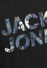 Musta kangas esitleb suurt, kaunistatud kirja "JACK JONES" erksates lillemustrites, näidates sinise, rohelise, valge ja kollase toone.